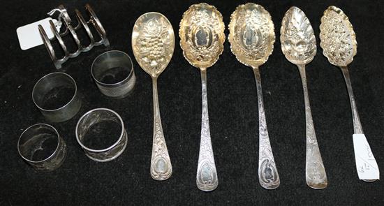 2 silver berry spoons, 3 plated berry spoons, a small plated toast rack and 4 silver napkin rings